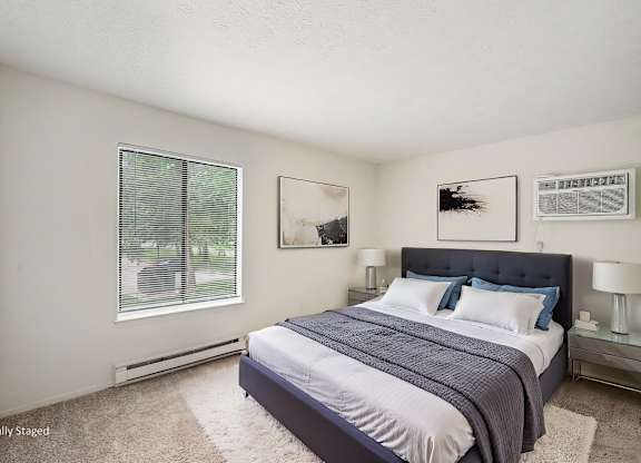 A bedroom with a bed, nightstands, and pictures on the wall.