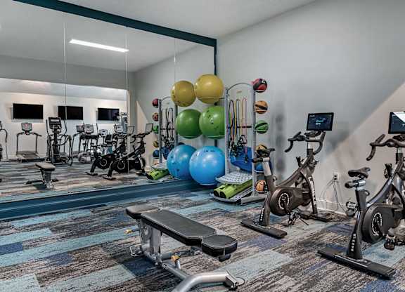 a gym with exercise equipment and mirror at Latitudes Apartments, Indianapolis, 46237