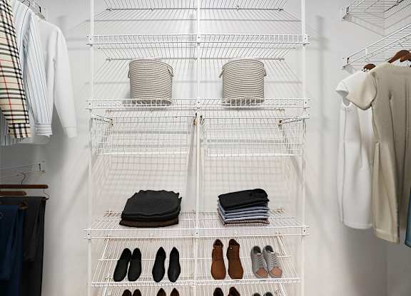A white closet with clothes and shoes organized on shelves at Foxwood and The Hermitage in Portage, MI