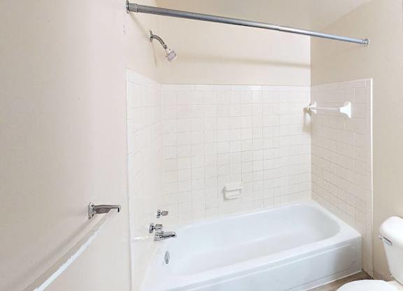A full bathroom with a tub, toilet, and shower at Glen Oaks Apartments, Michigan, 49442