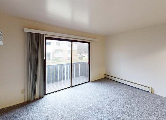 A living room with carpeting and a sliding glass door at Glen Oaks Apartments, Michigan, 49442