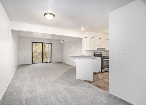 a living room and kitchen with a door to a balcony at Glenn Valley Apartments in Battle Creek, MI