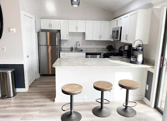 A community building kitchen with white cabinets and a breakfast bar at Granada Apartments, Jackson
