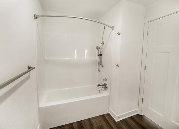 A white bathroom with a bathtub and a shower at The Grove Apartment Homes in Lincoln, NE