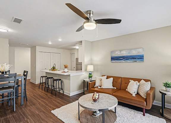 A living room with a brown couch and a ceiling fan at The Grove Apartment Homes, Nebraska