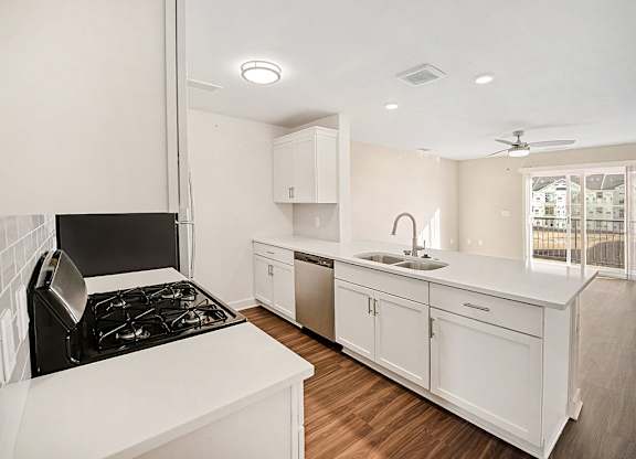 A modern kitchen with white cabinets and a breakfast bar at The Grove Apartment Homes in Lincoln, NE