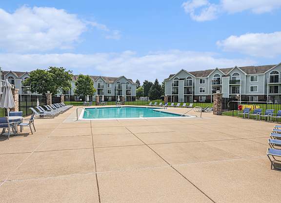 A large outdoor swimming pool surrounded by lounge chairs at Gull Prairie/Gull Run Apartments and Townhomes, Kalamazoo