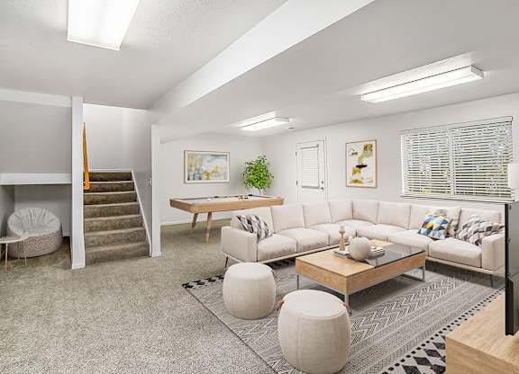 A basement recreation room with a grey carpet and a sofa at Gull Prairie/Gull Run Apartments and Townhomes, Michigan, 49048