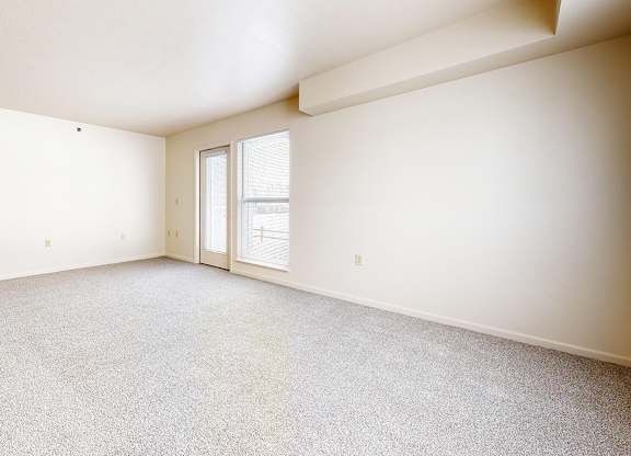 An enlarged living room with a carpeted floor and a door leading to a patio at Gull Prairie/Gull Run Apartments and Townhomes, Kalamazoo, 49048