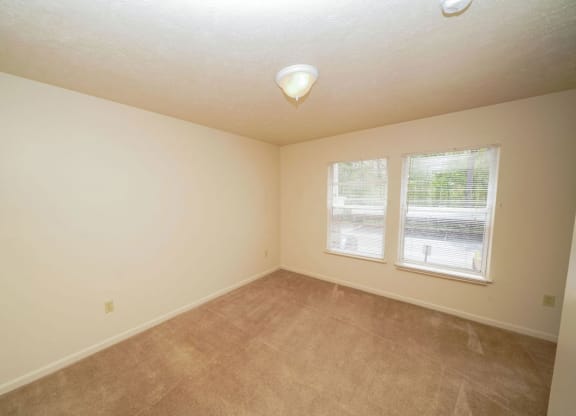 Bedroom with plush carpeting and two windows at Glenn Valley Apartments, Michigan