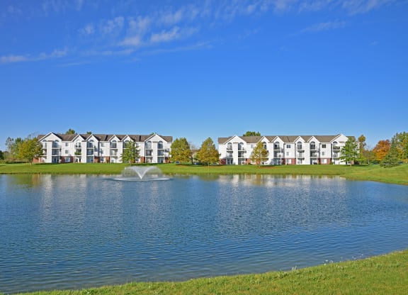 a lake with a fountain in front of a building at Heatherwood Apartments, Grand Blanc