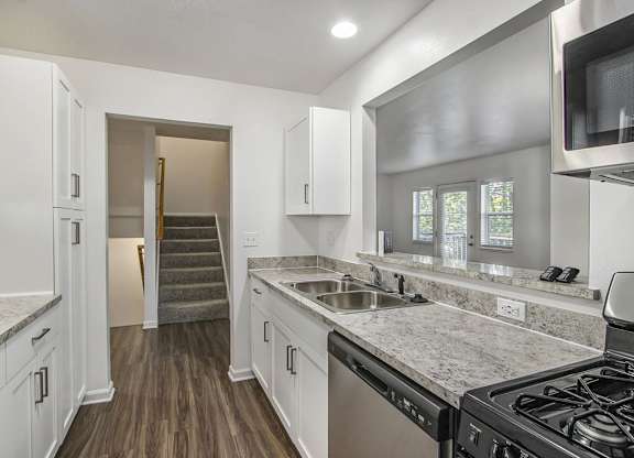A kitchen with white cabinets and a breakfast bar at Foxwood and The Hermitage, Portage, MI, 49024