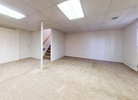 A basement recreation room with white walls and carpeted floor at Foxwood and The Hermitage, Michigan