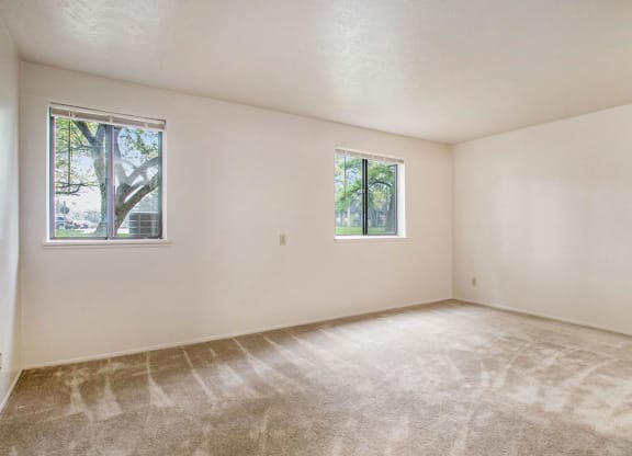 a bedroom with two windows and a carpeted floor at Hickory Village Apartments, Indiana, 46545