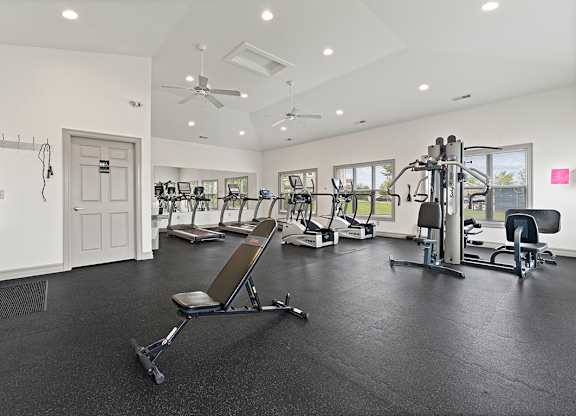 A spacious gym with a variety of equipment including a treadmill, a stationary bike, a rowing machine, and a weight bench at Hunters Pond Apartment Homes, Illinois, 61820