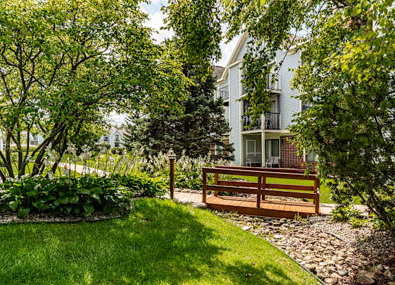 A bench is situated in a garden with a building in the background