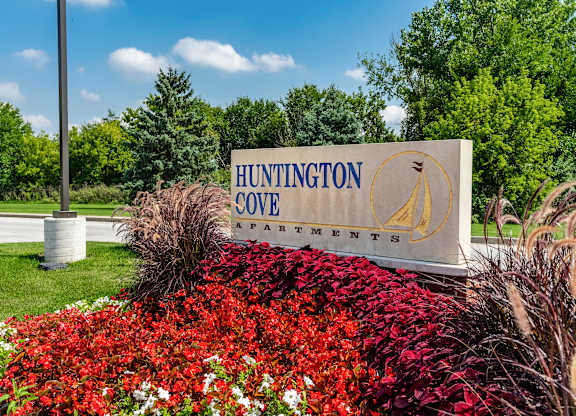 A sign for Huntington Cove Apartments is surrounded by flowers