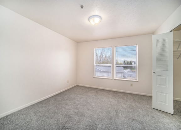 Large bedroom with a walk-in closet and two windows at Hurwich Farms Apartments, Indiana