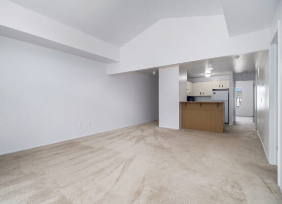 the living room and kitchen of an empty house with white walls and flooring at Hurwich Farms Apartments South Bend, IN