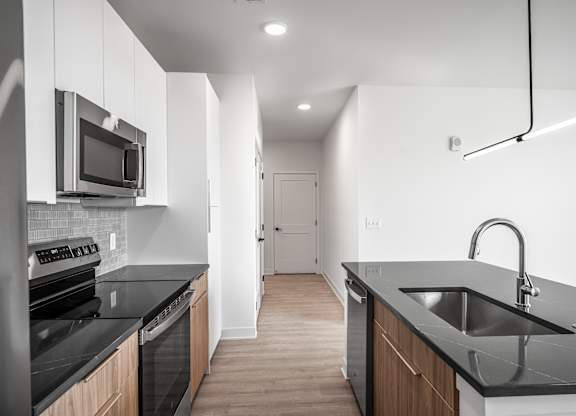 A modern kitchen with black countertops and wooden cabinets.
