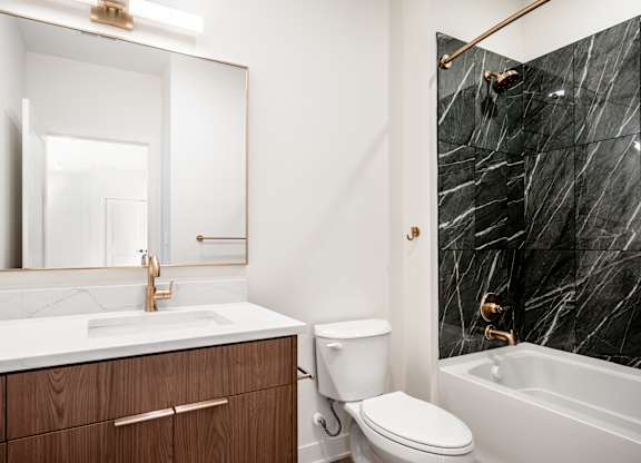 A bathroom with a marble wall and a white sink.
