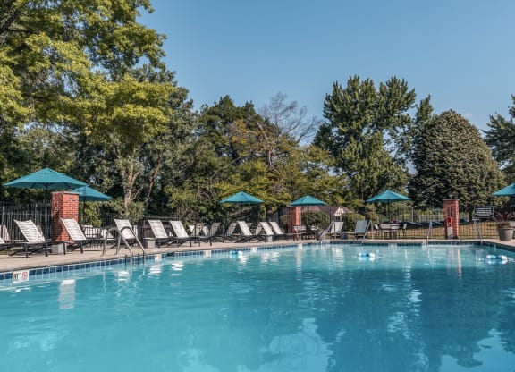 a swimming pool with chairs and umbrellas at Polo Run Apartments, Indiana