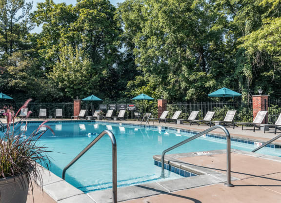 a swimming pool with chairs and trees in the background at Polo Run Apartments, Greenwood, IN