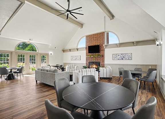 A large black table surrounded by chairs in a room with a brick fireplace at Indian Lakes Apartments, Mishawaka, Indiana