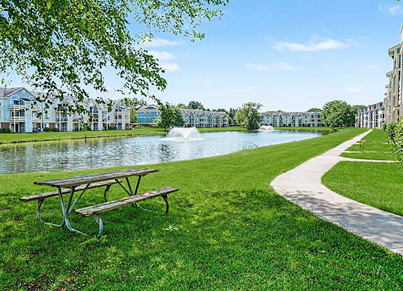 A picnic table sits on a grassy area next to a pond at Indian Lakes Apartments, Mishawaka, Indiana