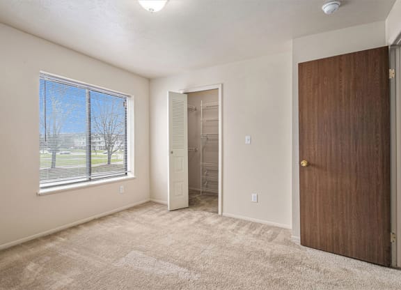 Bedroom with a large window and a door to a closet at Indian Lakes Apartments, Mishawaka