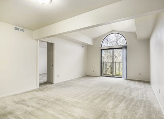 an empty living room with a large window and a door to a balcony at Indian Lakes Apartments, Mishawaka, Indiana