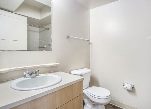 A bathroom with a toilet, sink and mirror at Indian Lakes Apartments, Mishawaka, IN