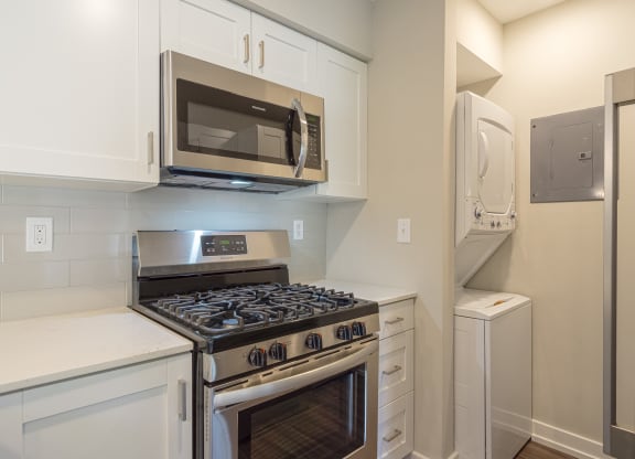a kitchen with white cabinets and stainless steel appliances at Hillside Apartments, Wixom, MI