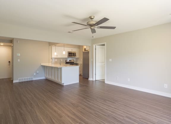 an empty living room with a kitchen in the background at Hillside Apartments, Michigan, 48393