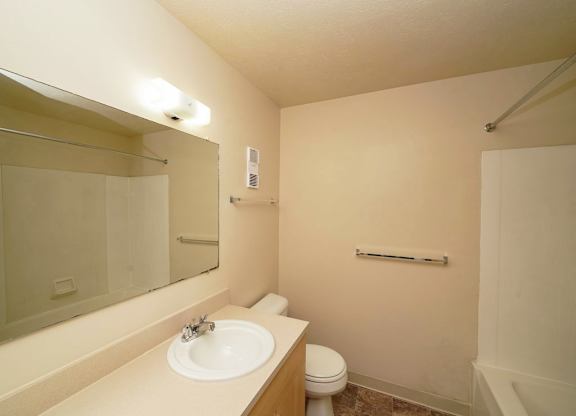 A bathroom with a toilet, sink, and mirror at Irish Hills Apartments, South Bend, IN