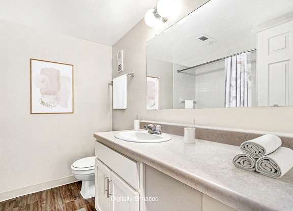 An upgraded bathroom with a toilet, sink, and large vanity with a mirror at Irish Hills Apartments, South Bend, Indiana