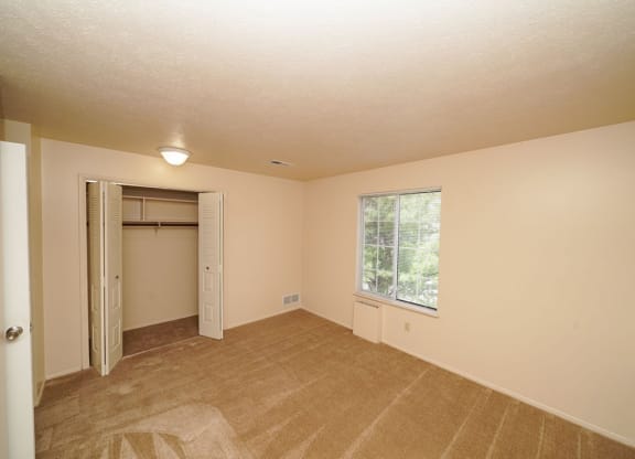 A spacious bedroom with a window and a closet at Irish Hills Apartments, South Bend