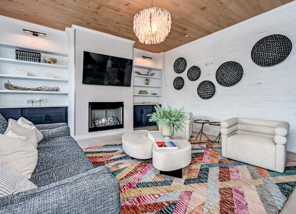 A living room with a grey couch, a white armchair, a white coffee table, a fireplace, and a wooden ceiling at Ironwood Flats Apartments, Florida, 33511