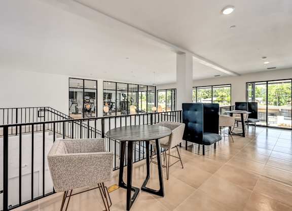 A modern living room with a black railing and a round table with chairs at Ironwood Flats Apartments, Brandon, FL, 33511