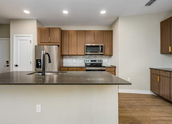 A kitchen with a stainless steel refrigerator, microwave, and oven.