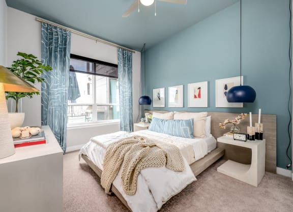 a bedroom with blue walls and a large window with blue curtains at Ironwood Flats, Brandon, Florida