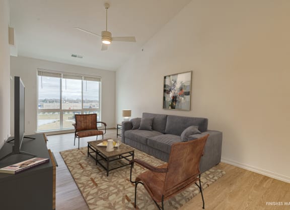 a living room with a gray couch and two brown chairs  at Uptown Square Apartments, Troy