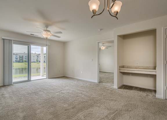 A spacious room with a ceiling fan and a large window with a view of a building outside.