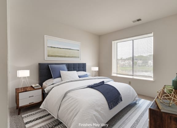 a bedroom with a bed and two windows at The Landings Apartments, Michigan