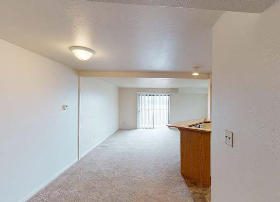 A dining room leading to a living room with sliding glass doors to a balcony at Liberty Mills Apartments, Fort Wayne