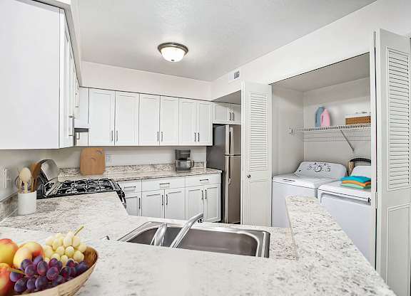 A kitchen with a marble counter top and white cabinets