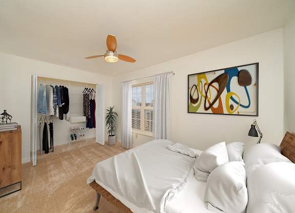 a bedroom with a bed, a ceiling fan and a closet with organizers at Limestone Creek Apartment Homes, Madison, AL