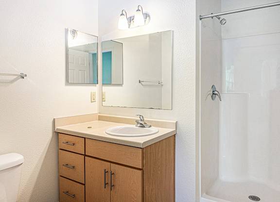 A bathroom with a sink, mirror, and shower at Limestone Creek Apartment Homes, Madison, AL