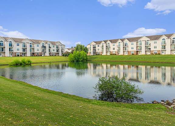 A row of apartments are reflected in the water of a pond at Limestone Creek Apartment Homes, Madison, AL
