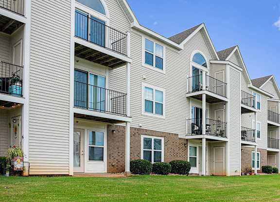 An exterior rear apartment building view of balconies and patios with private storage spaces at Limestone Creek Apartment Homes, Madison, AL